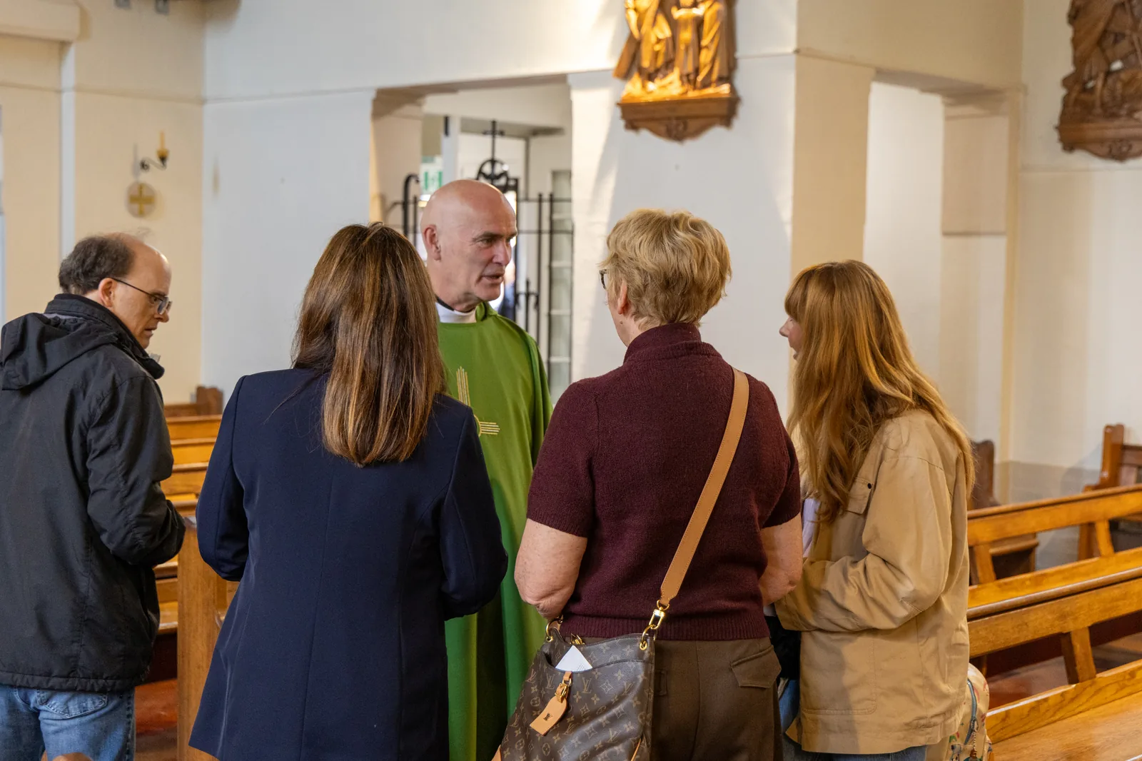 Priest speaking with parishioners inside Our Lady of Walsingham Church