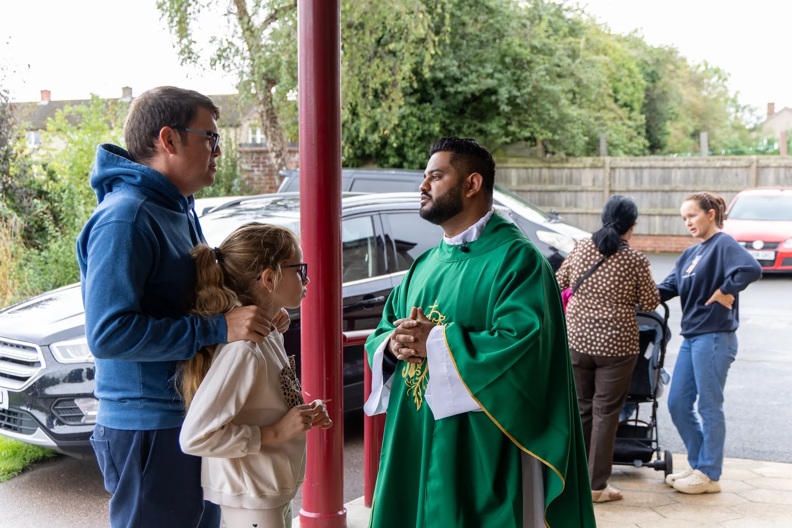Priest speaking with a family outside St Brendan’s Church